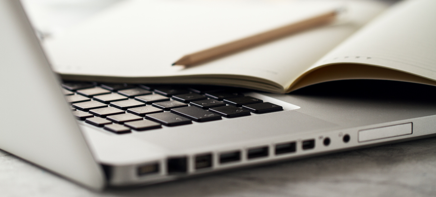 Computador com um caderno em cima do teclado